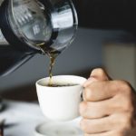 pouring brewed coffee in a white cup