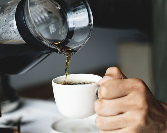 pouring brewed coffee in a white cup