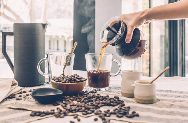 A person putting black coffee into a mug