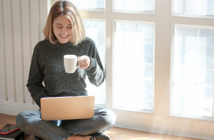 a woman drinking coffee and using laptop