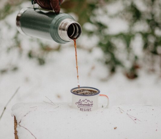 a person pouring coffee from a travel coffee mug
