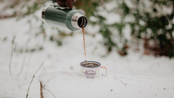 a person pouring coffee from a travel coffee mug