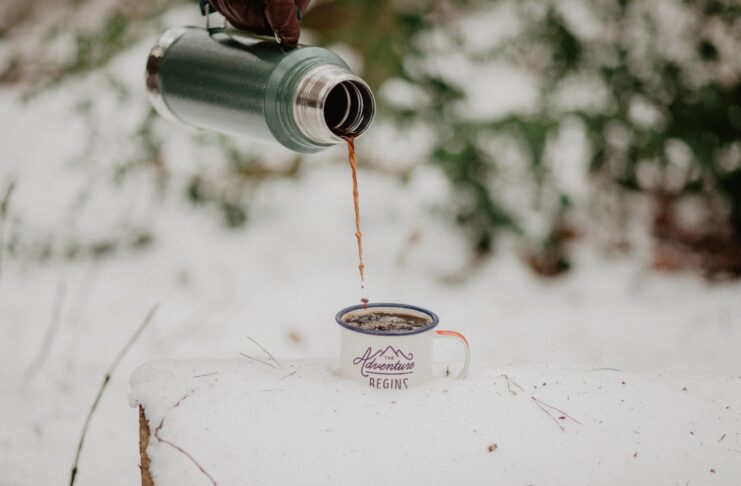 a person pouring coffee from a travel coffee mug