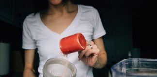 a woman adding a scoop of protein powder