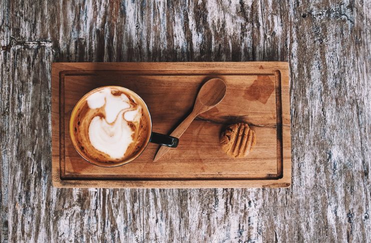 a cup of Macchiato along with a cookie and spoon